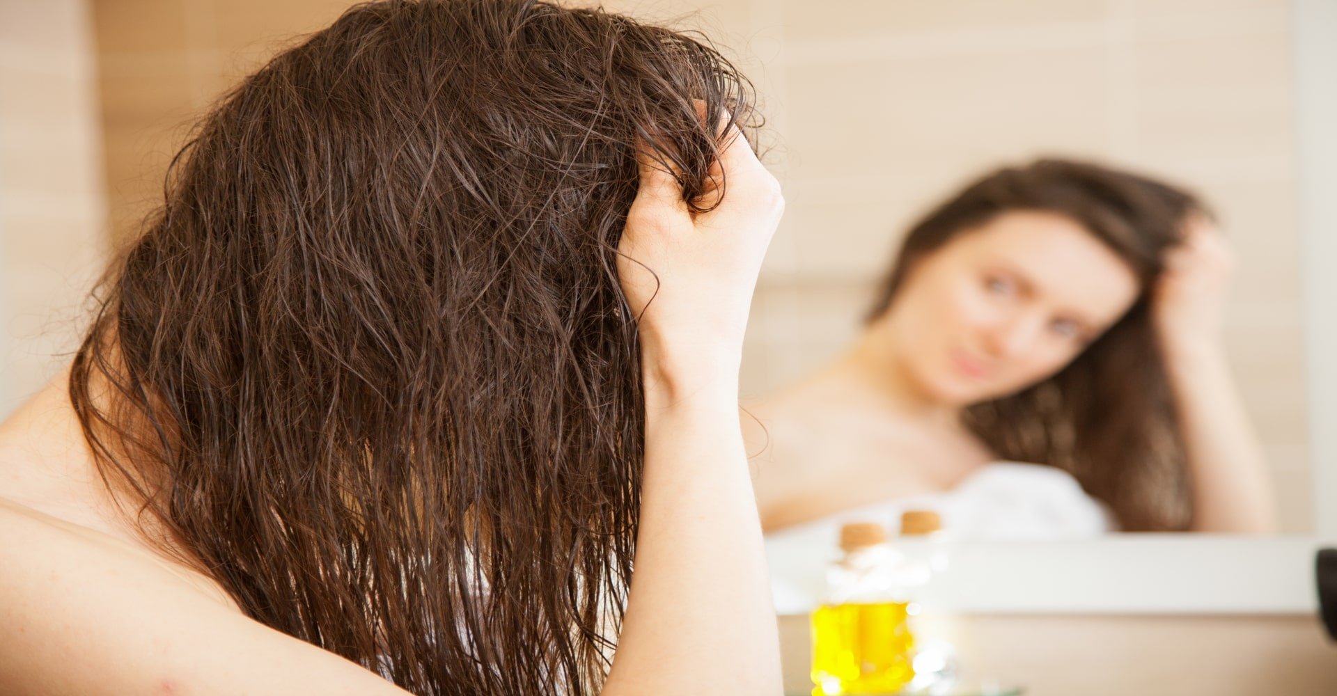Modelo branca de olhando no espelho passando a mo no cabelo